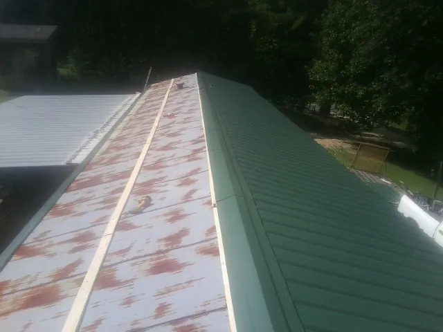 Old rusted panels beside newly installed green metal roofing — Wind Damage Roof Repair by Roofing Brothers in Berlin Heights