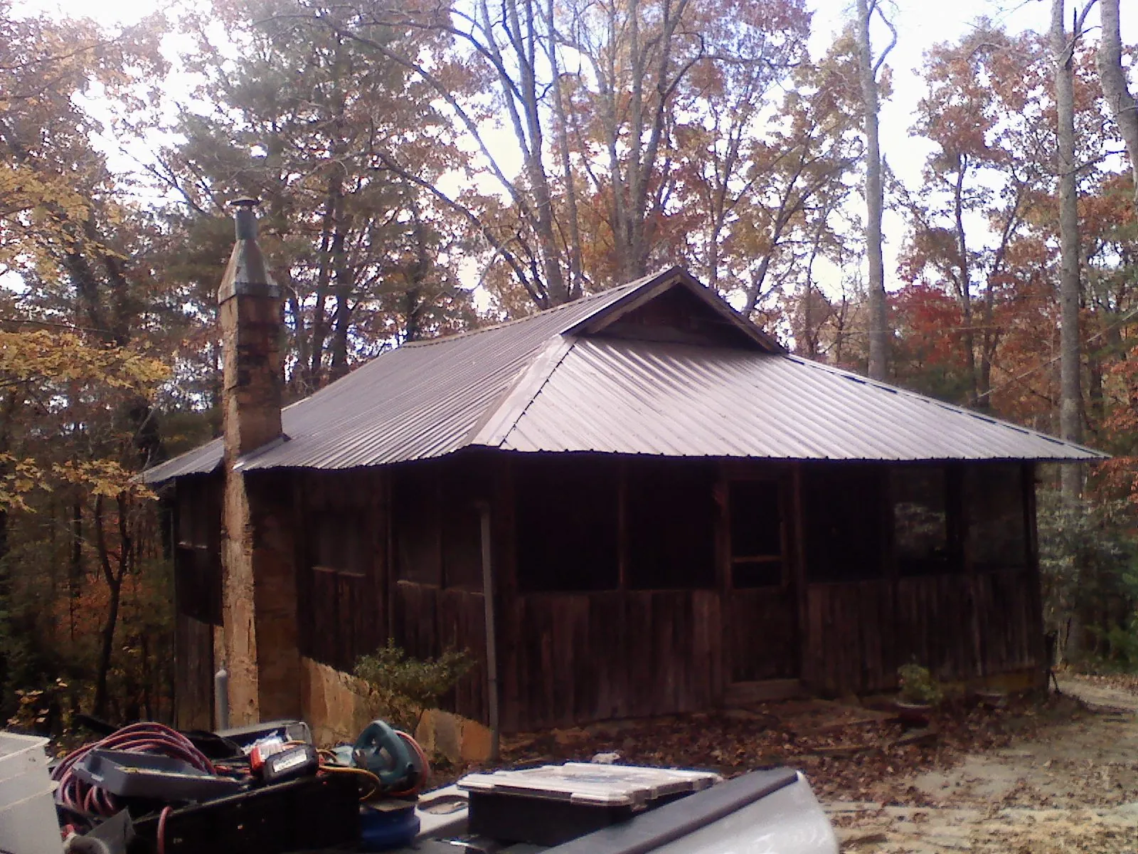 Brown metal hip roof on an old cabin with a stone chimney in Berlin Heights
