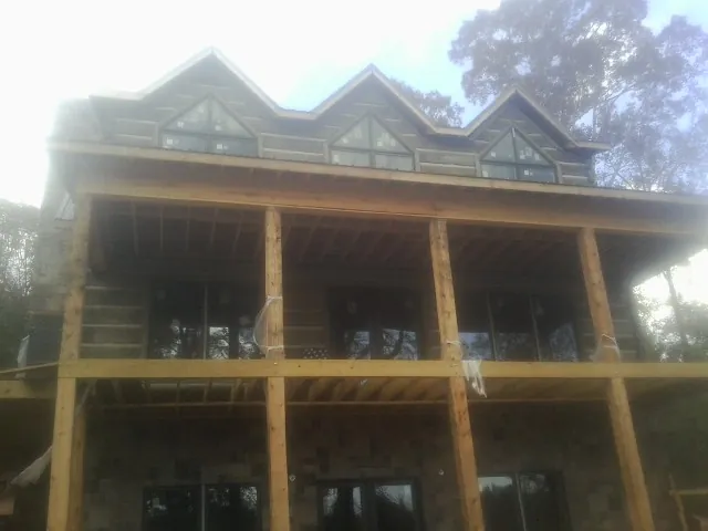 Dormers and porch framing on a large log home under construction — Roof Coating work by our crew in Berlin Heights