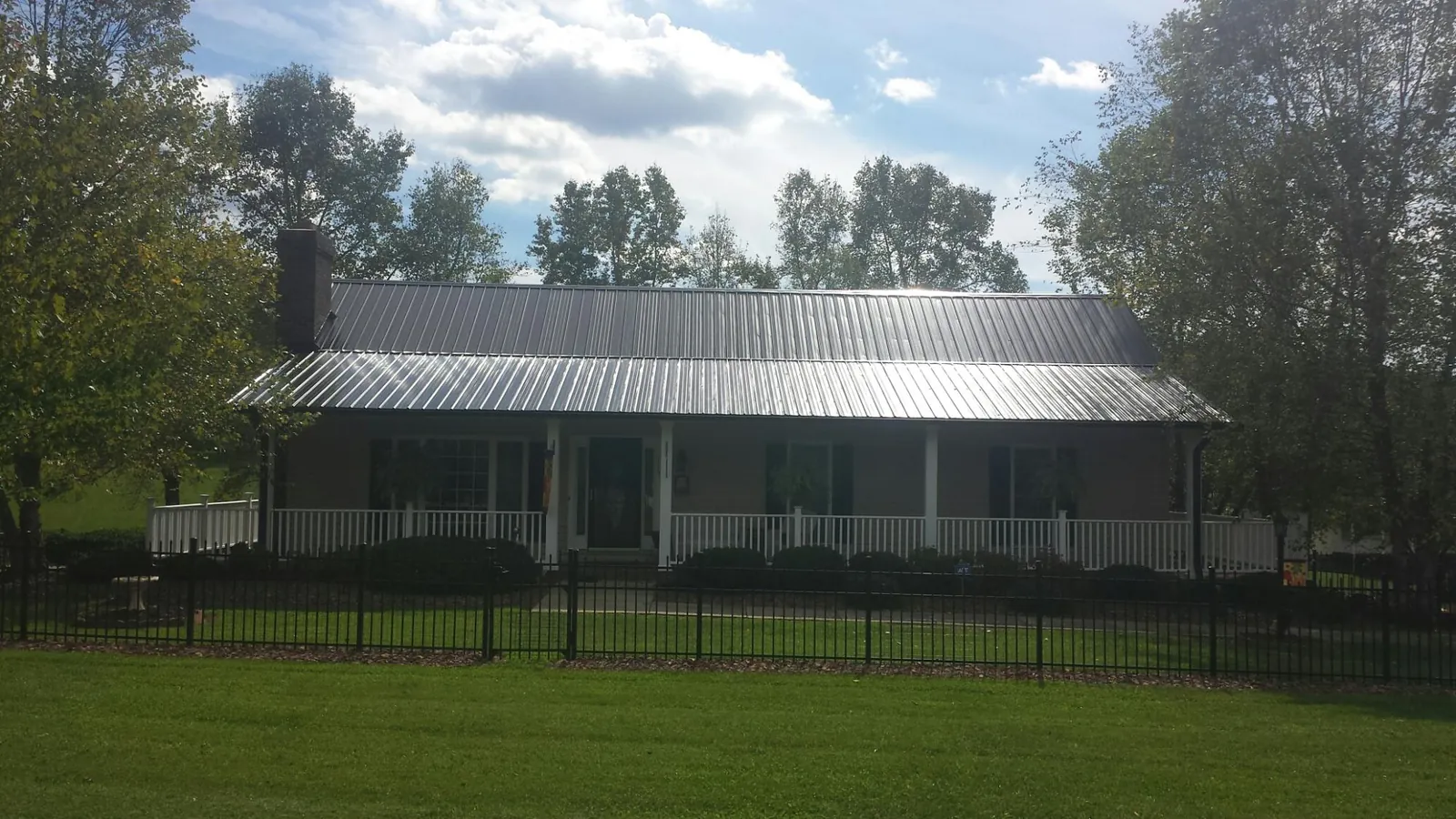 Gray metal roof on a brick ranch with a full width front porch — Gutter Guard Installation work by our crew in Berlin Heights