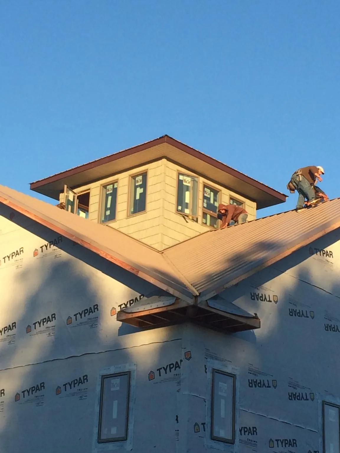 Roofers working around a rooftop cupola on a new metal roof at sunset — Roof Waterproofing in Berlin Heights by Roofing Brothers
